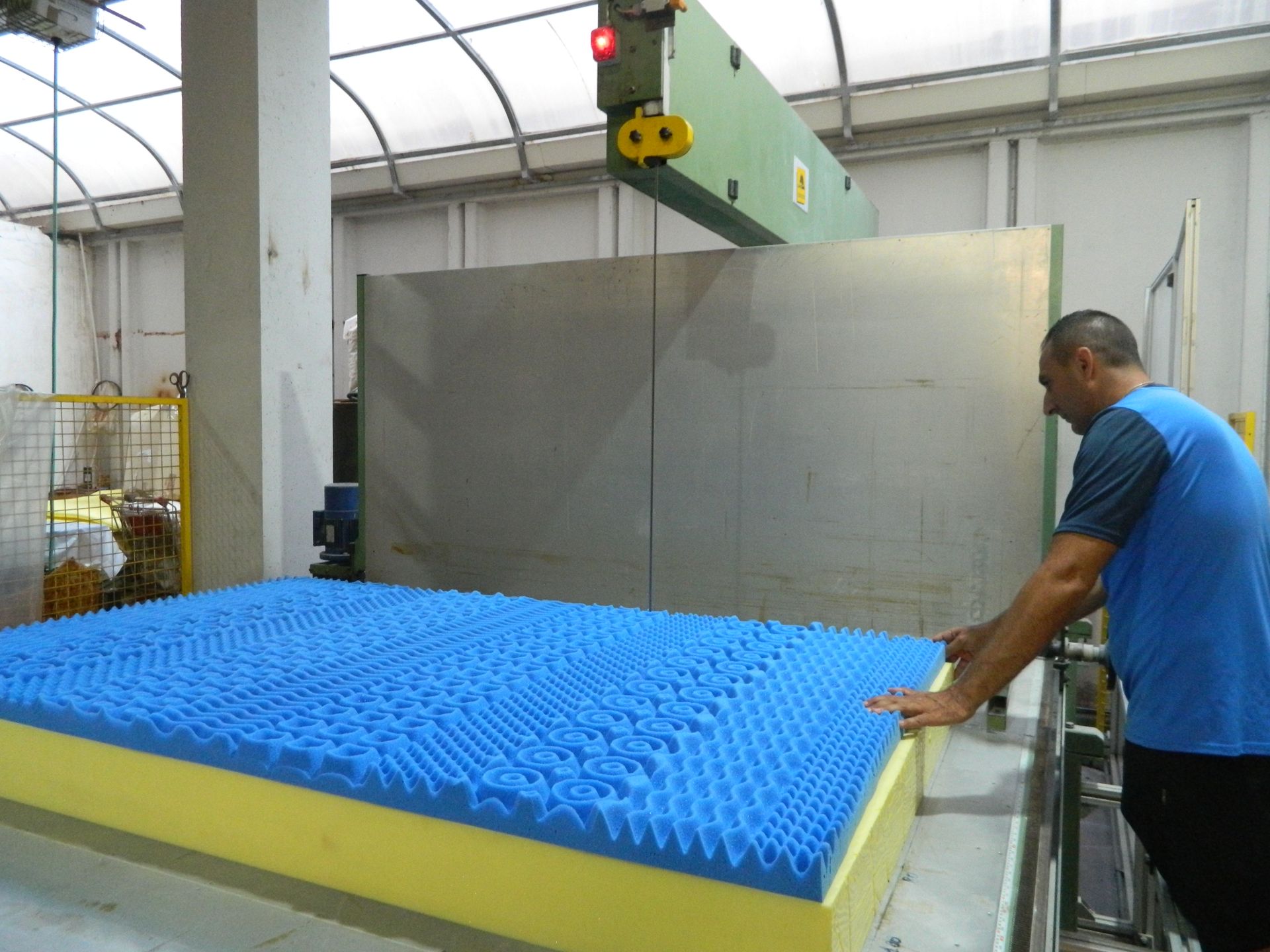 Un uomo con una camicia blu sta lavorando su un materasso