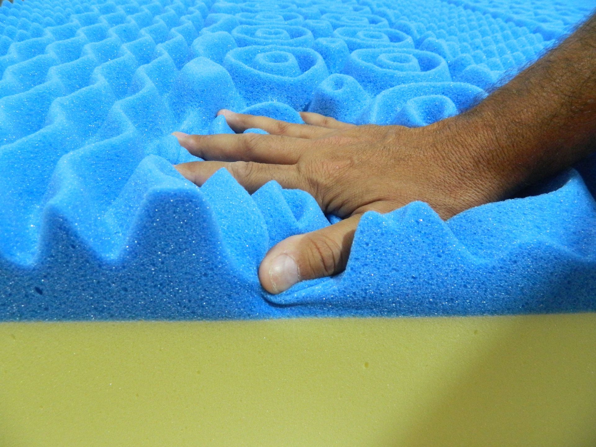 La mano di una persona è su un materasso di schiuma blu