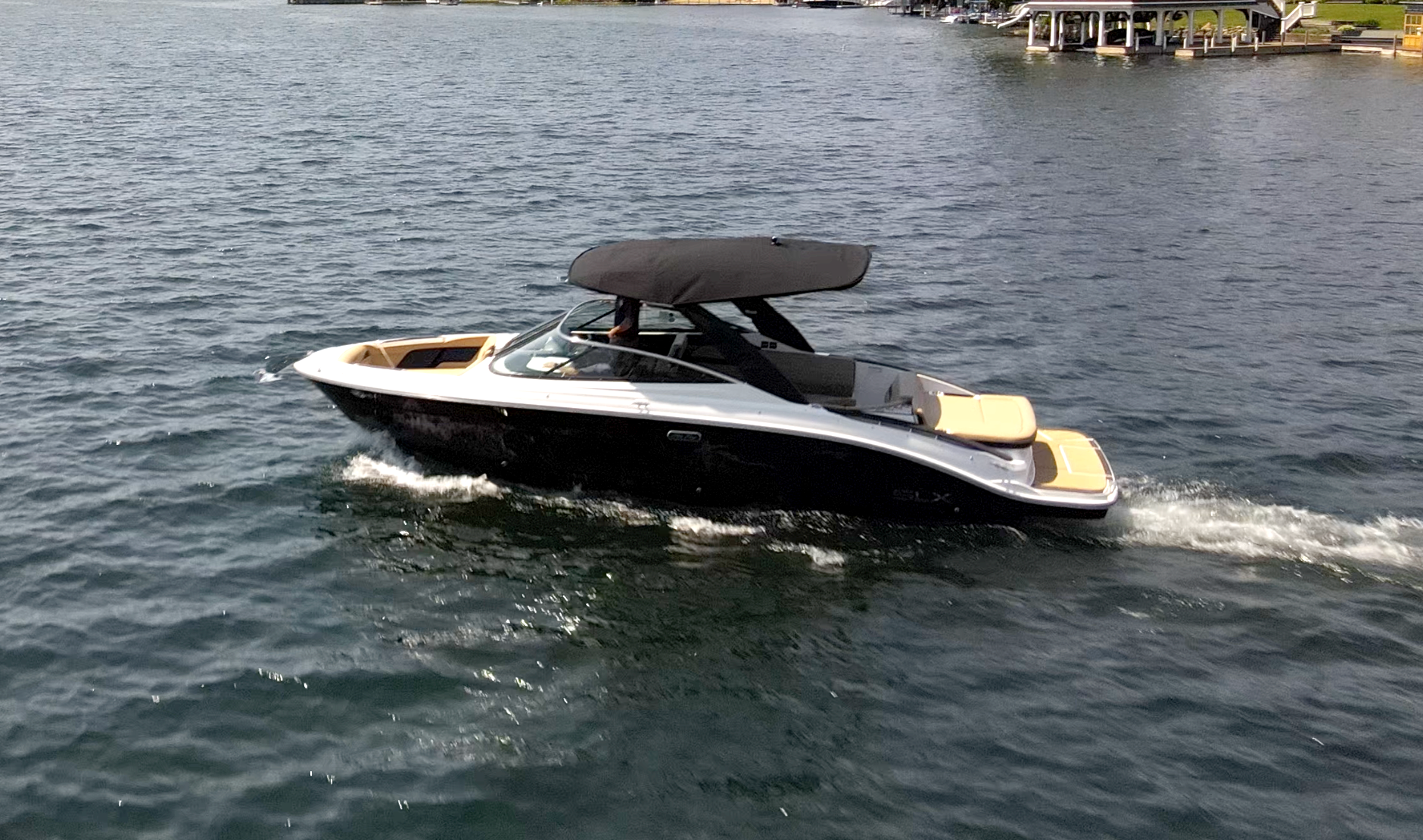 Black and white motorboat cruising on a lake, producing a white wake.