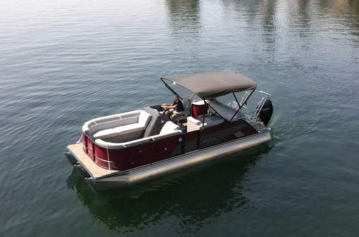 Pontoon boat on water with a dark red exterior and black canopy.