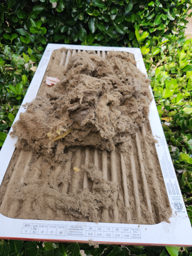 A dirty air filter is sitting on top of a white box.