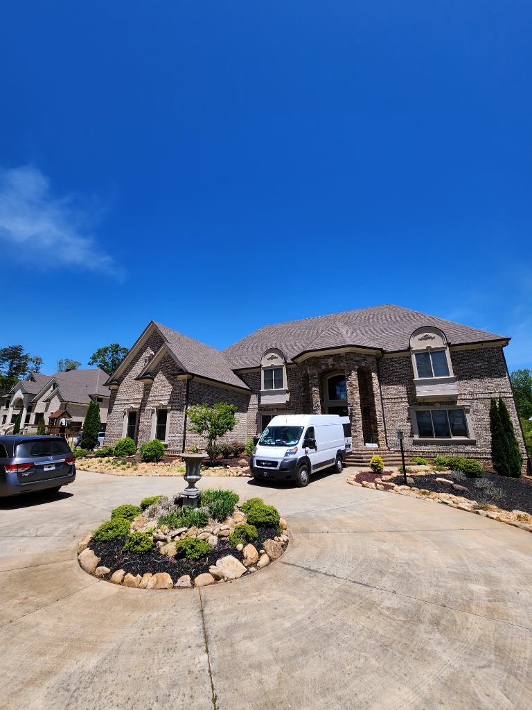 A white van is parked in front of a large house.