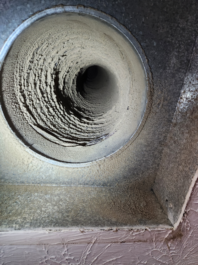 A close up of a dirty air vent on a wall.