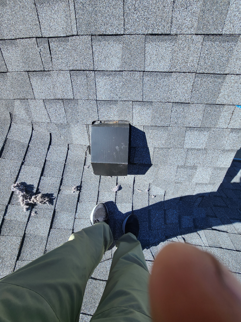 A person is standing on a roof with a box on it.