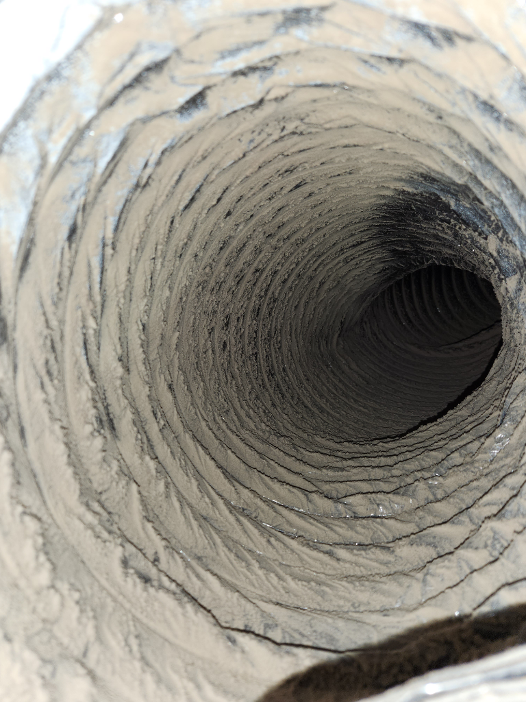 A close up of a dirty air duct with a hole in the middle.