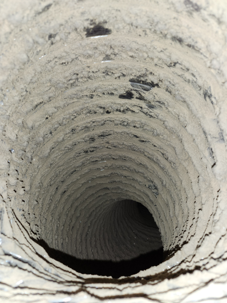 A close up of a dirty air duct with a hole in the middle.
