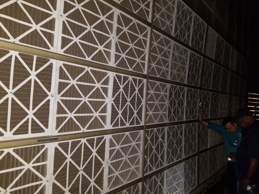 Two men are standing in front of a wall of filters