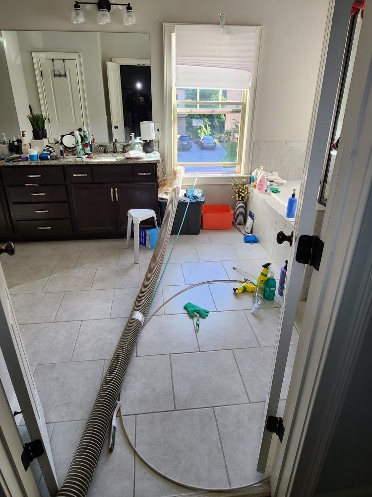 A bathroom with a vacuum hose attached to the floor.
