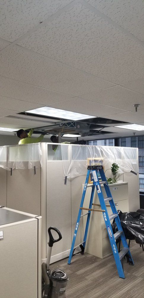 A ladder is sitting in the middle of a room in an office.