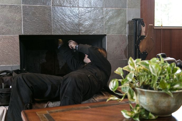 A man is working on a fireplace in a living room