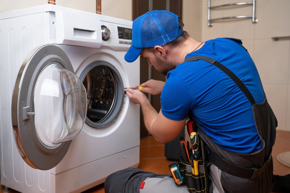 a man is fixing a washing machine in a bathroom .