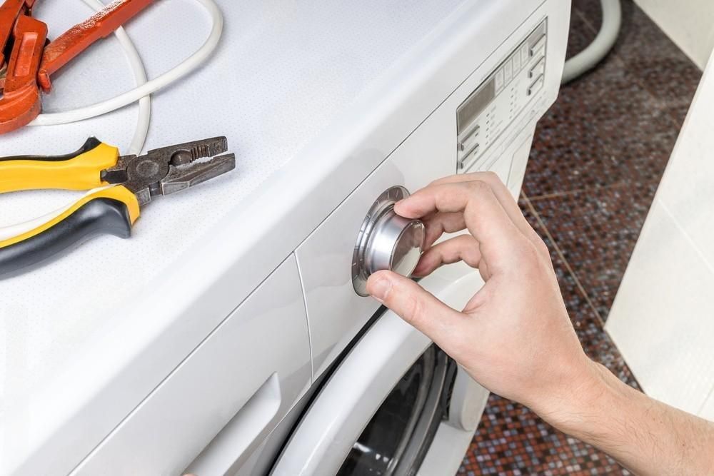 a person is turning a knob on a washing machine .