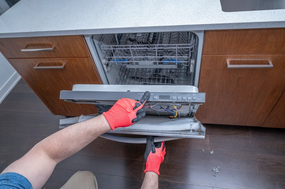 a man is fixing a dishwasher in a kitchen .