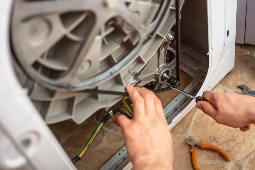 a person is fixing a washing machine with a screwdriver .