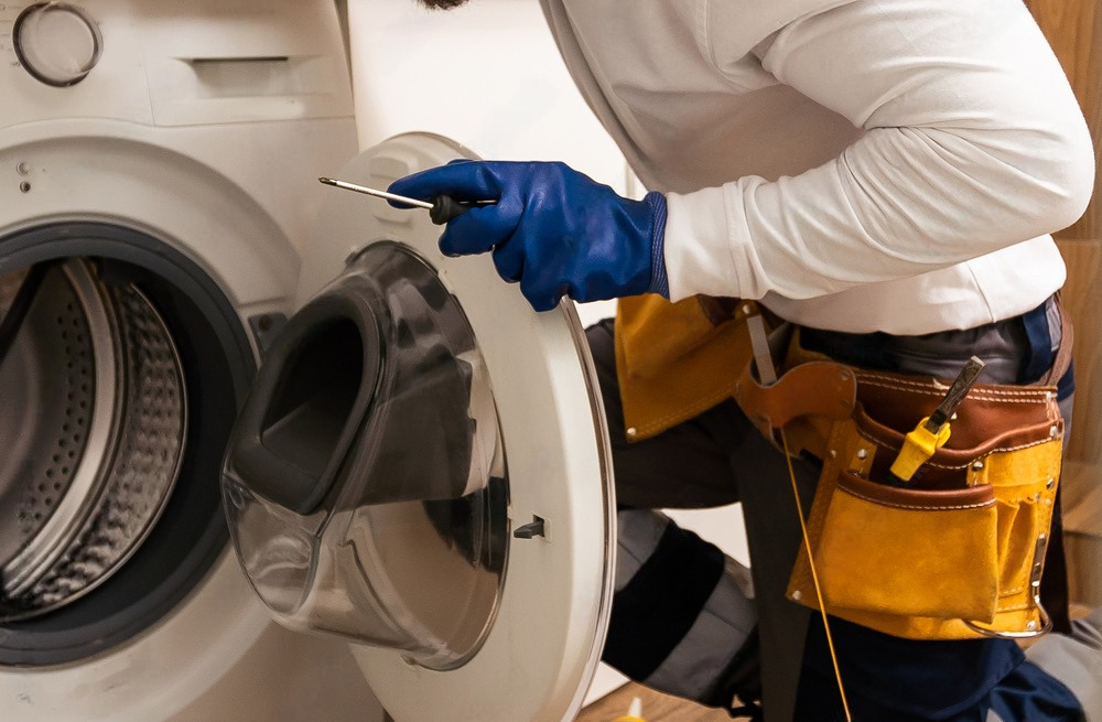 a man is fixing a washing machine with a screwdriver .