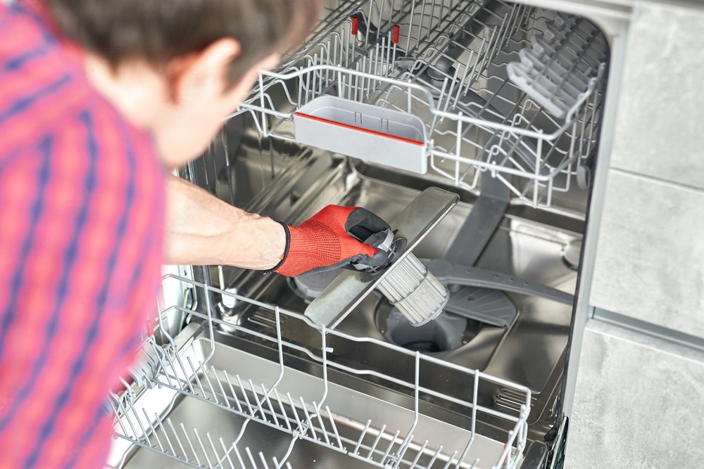 a man is cleaning a dishwasher in a kitchen .