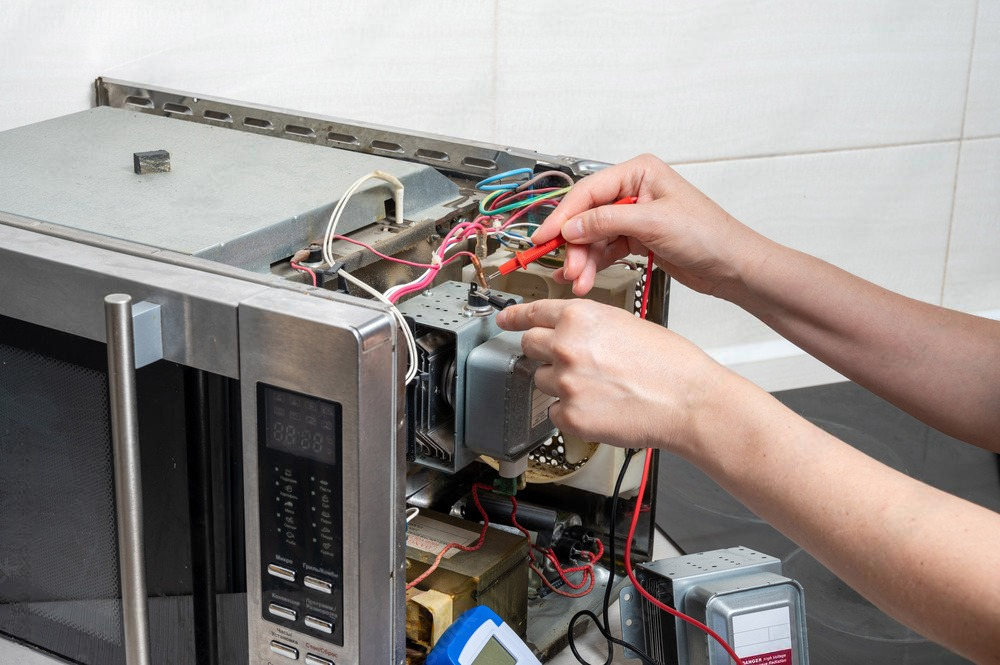 a person is fixing a microwave oven with a multimeter .