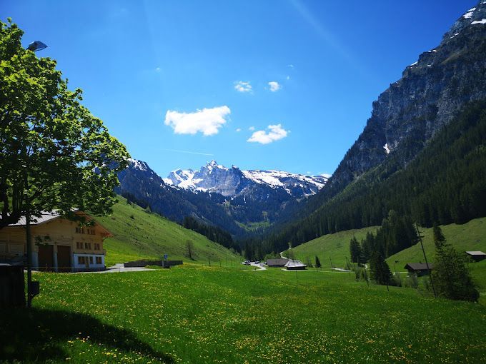 Ein Tal mit Bergen im Hintergrund und einem Haus im Vordergrund