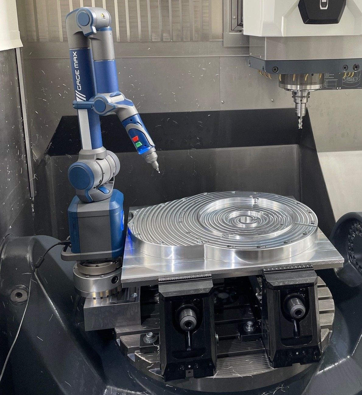 Ein blauer Roboterarm untersucht ein silbernes, kreisförmiges Metallteil auf einer CNC-Maschine.