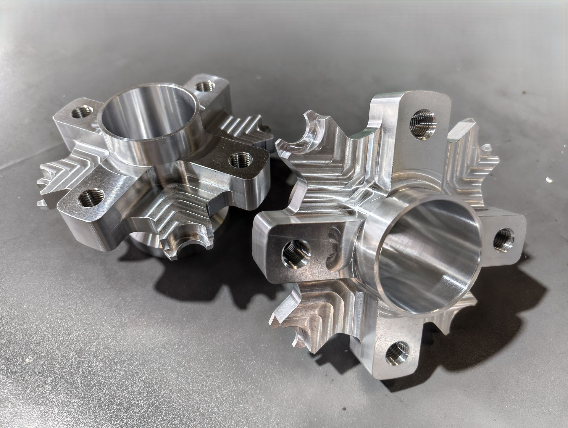 Nahaufnahme eines Gitters aus glänzenden, maschinell bearbeiteten Metallkomponenten mit aufwendigen Mustern und Löchern.