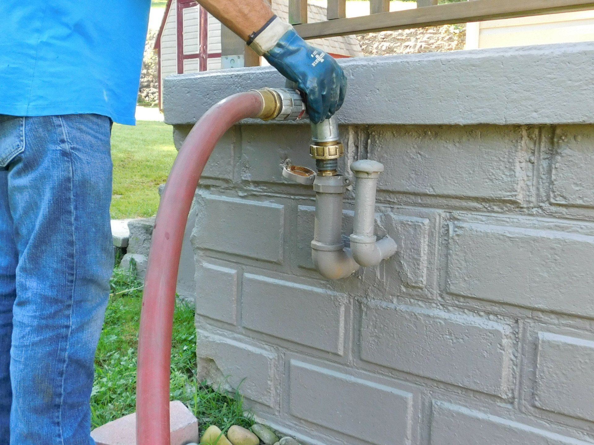 A Man Wearing Blue Gloves Is Pumping Water Into A Pipe — Dunbar, PA — Action Oil