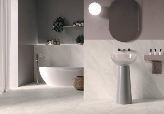 Moderna kopalnica z belo kadjo, umivalnikom na podstavku in sivimi stenskimi ploščicami.