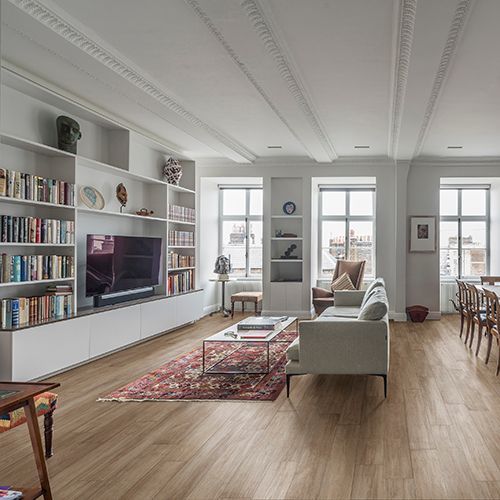 Prostorna dnevna soba z lesenimi tlemi, vgradnimi knjižnimi policami in kavčem.