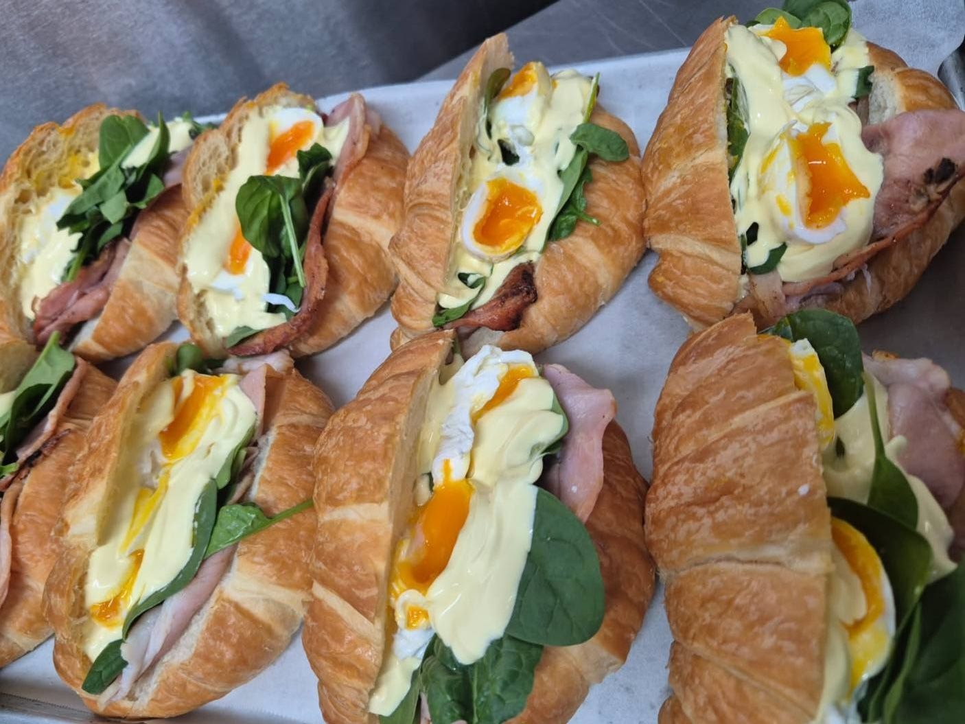 Croissants Filled With Poached Eggs, Ham, And Spinach, On A Metal Tray — Mels Catering in Garbutt, QLD