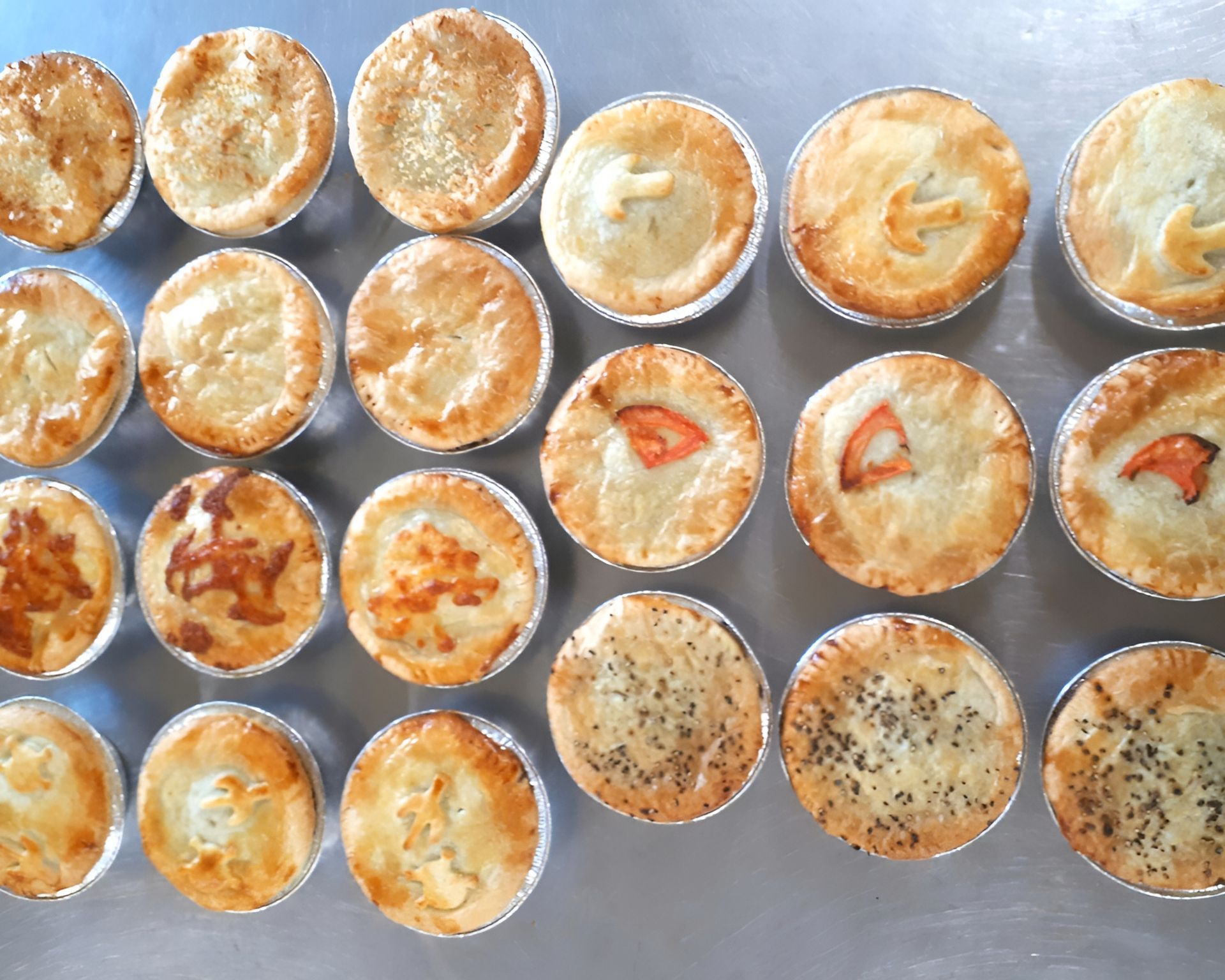 Rows of Baked, Golden-brown Savory Pies in Individual Foil Tins — Mels Catering in Longreach, QLD