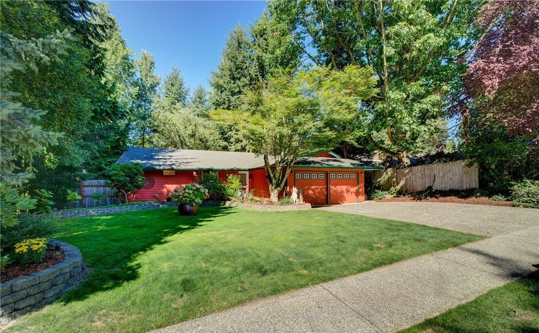 Person painting exterior of a house near a window, blue sky in the background.