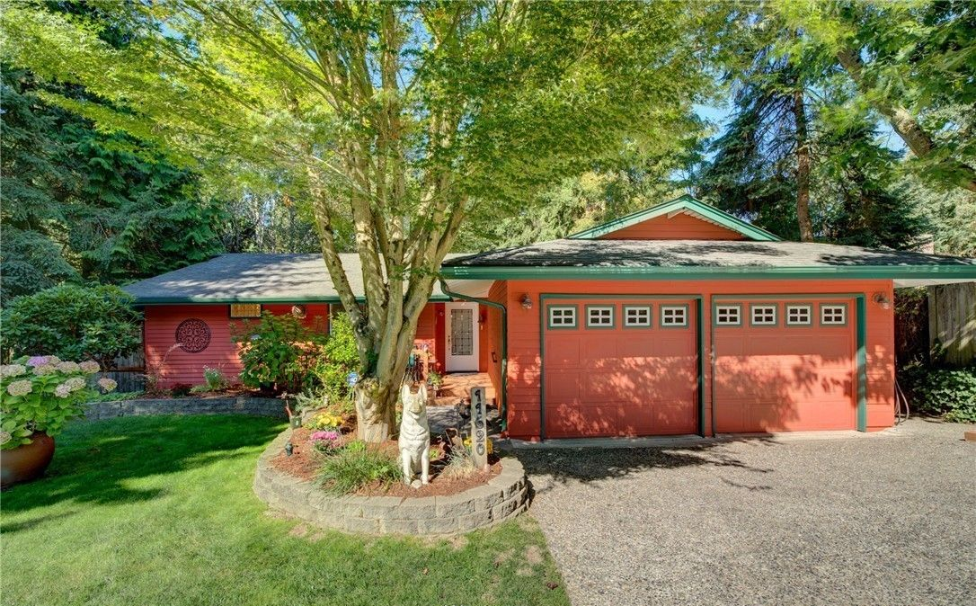 Two-story gray house with white garage door and driveway, under a partly cloudy sky.