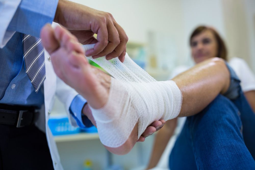 Doctor wrapping bandage around patient's injured foot.