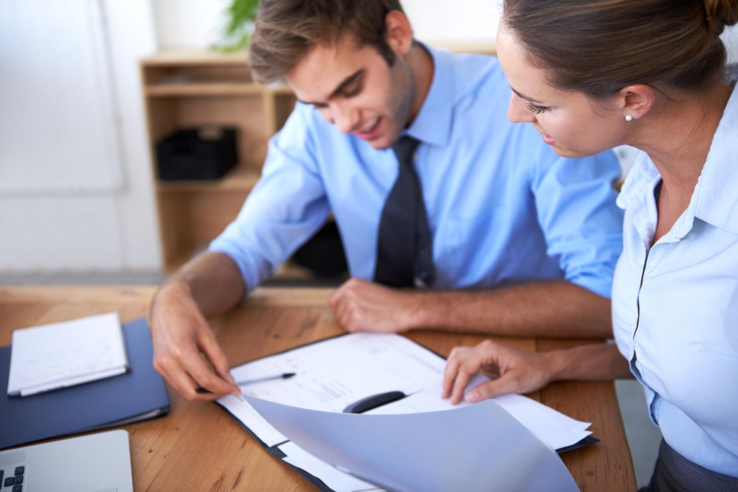 Man and woman reviewing paperwork together in an office setting.
