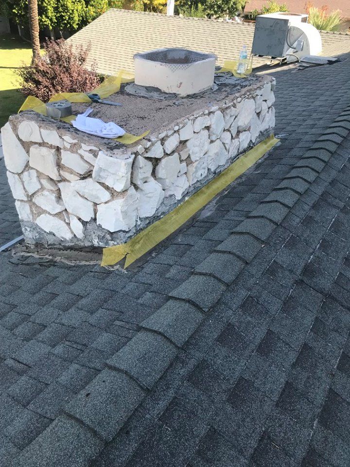 A stone chimney is sitting on top of a roof.