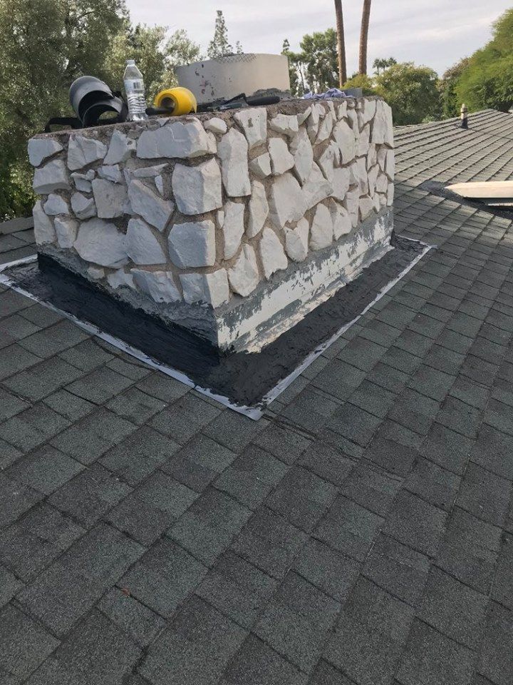 A stone chimney is sitting on top of a roof.