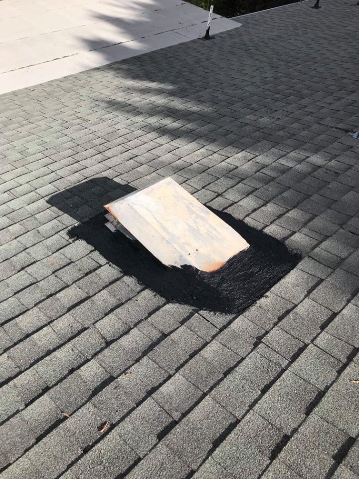 A piece of wood is sitting on top of a brick roof.
