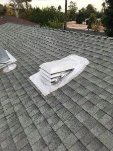 There is a vent on the roof of a house.