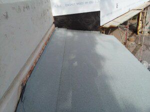 A gray carpet is being installed on the side of a building.