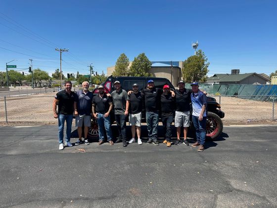 A group of men are posing for a picture in front of a truck.