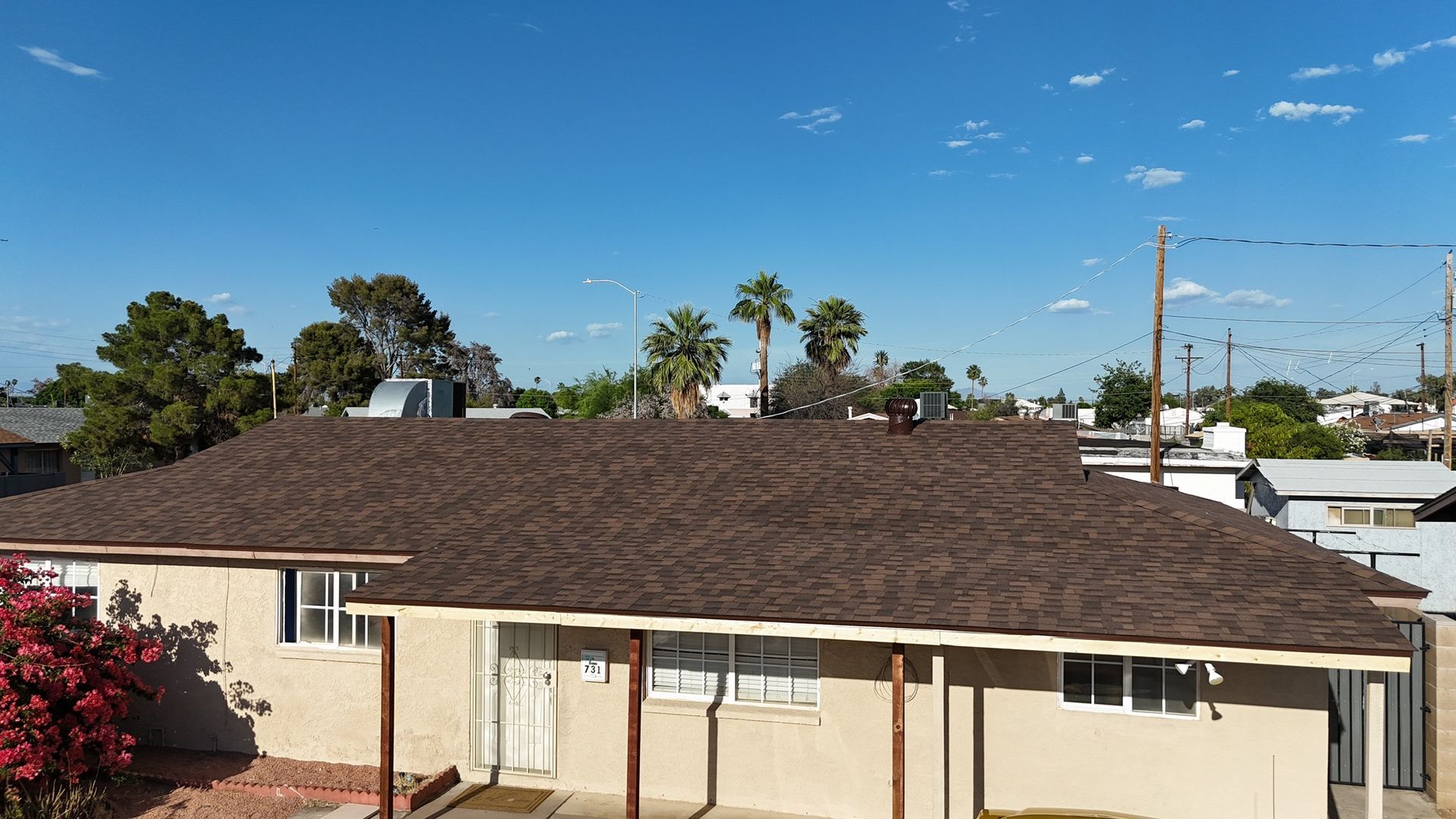 A house with a brown roof and a porch on a sunny day.