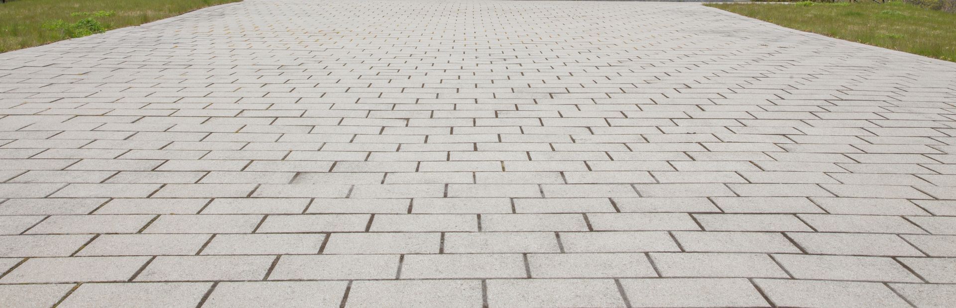 A close up of a brick walkway with grass on the side.