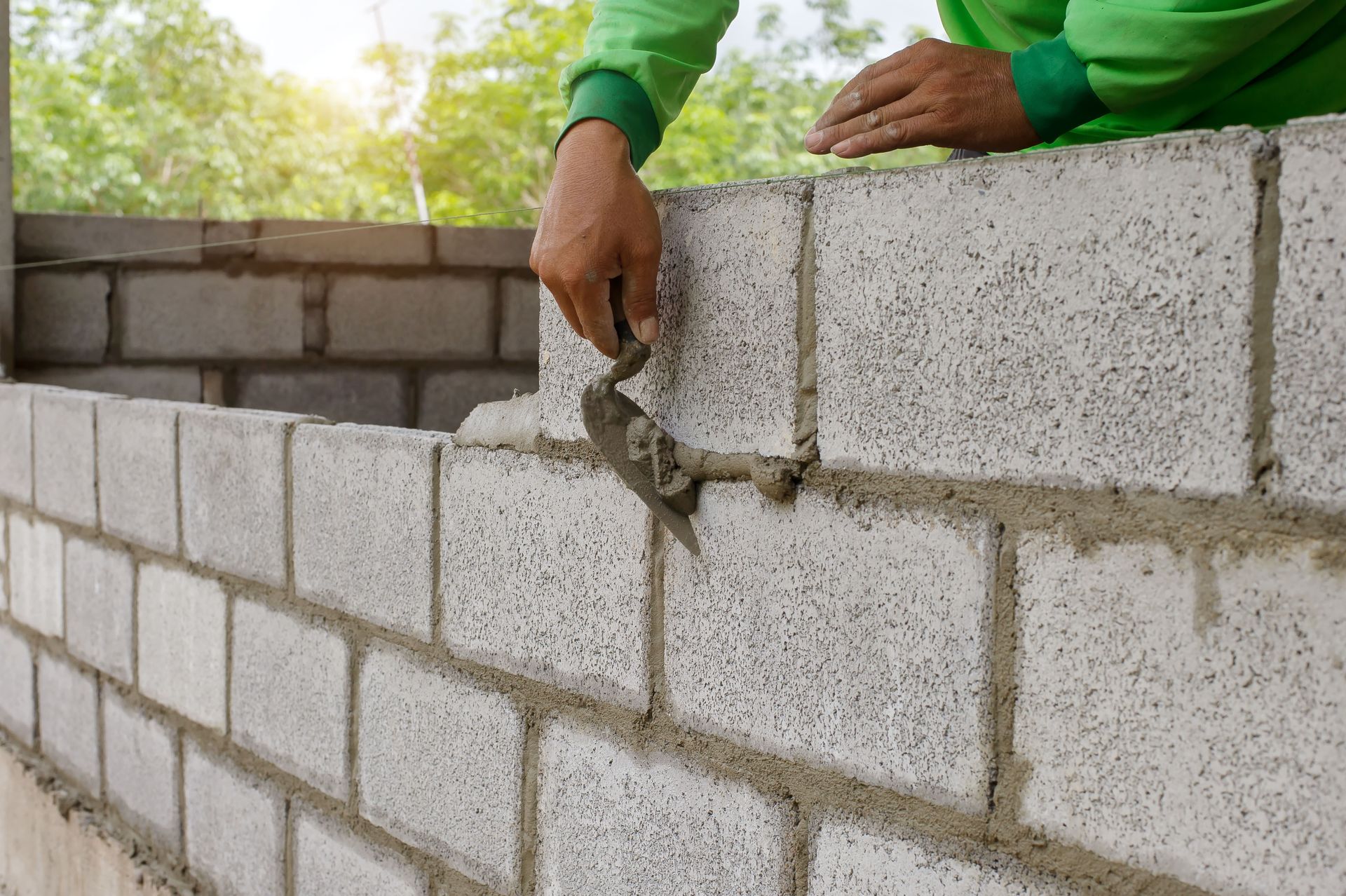 A man is laying bricks on a wall with a trowel.
