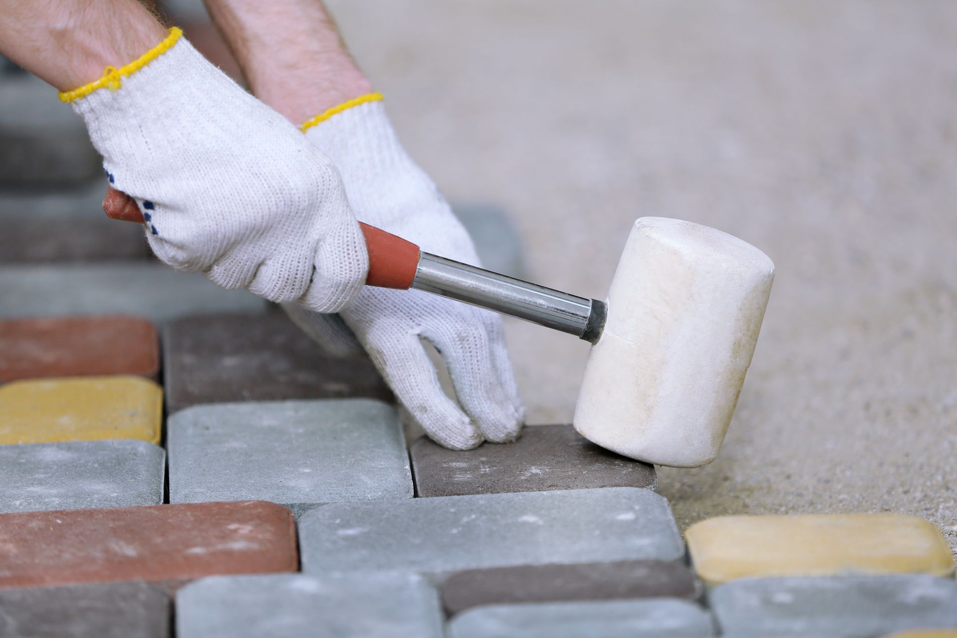 A person is using a rubber mallet to hammer bricks.