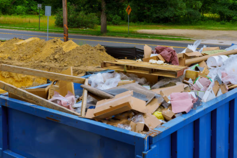 blue dumpster holding a bunch of wooden junk, plastic and land waste