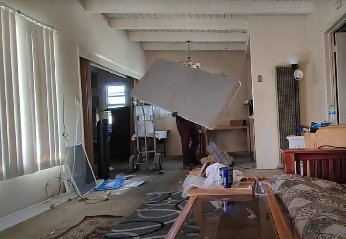our junk haulers carrying mattress through a living room for a house cleanout
