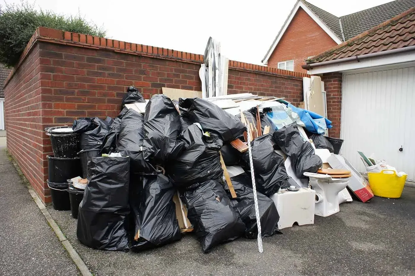 garbage bags collected next to side of brick wall