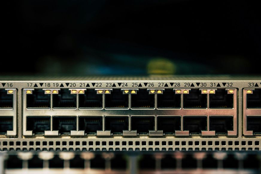Network switch with multiple ports lit with orange lights.