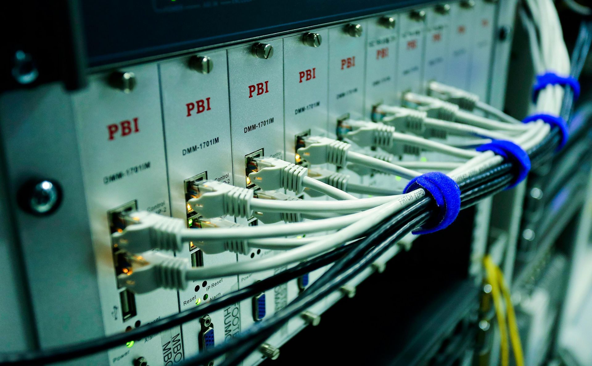 Server rack with white ethernet cables plugged in; cables are bundled with blue ties.