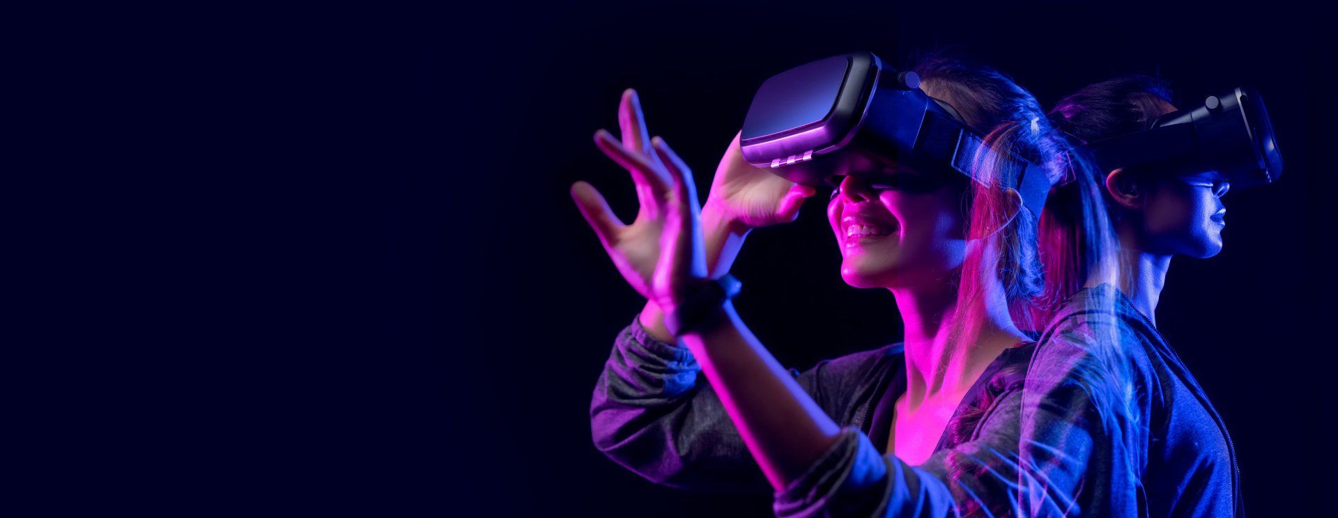 Woman in a dark room wearing a VR headset and smiling