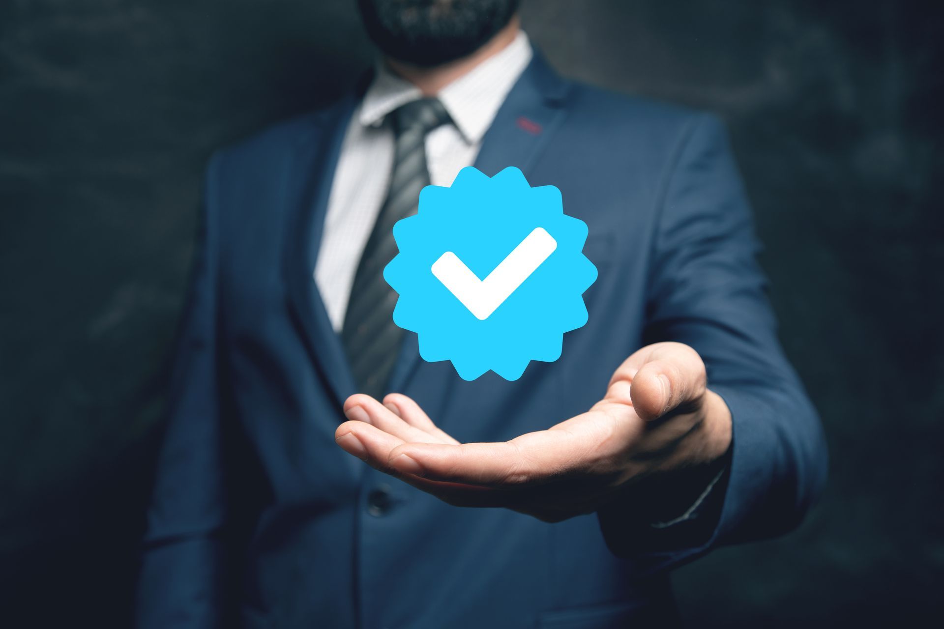 Man in a suit holding a floating blue tick symbol